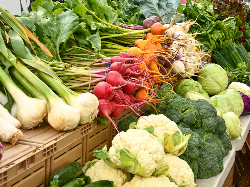 Crates of fresh vegetables including cauliflower, broccoli and radishes at a wholesale market.